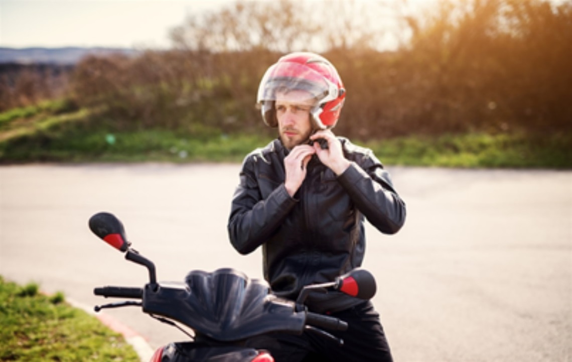 Person sitting on motorcycle adjusting helmet .jpg