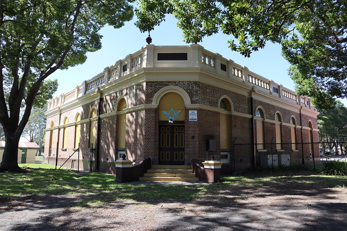 The rear exterior of the pavilion. There are a small set of stairs leadign up to the foyer doors. There is a Masonic square and compass sign above the doors for the Masonic hall on the left wing of the building.