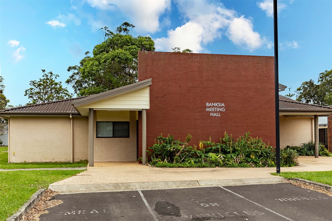 View of the front of Banksia Meeting Hall with carpark spaces. 