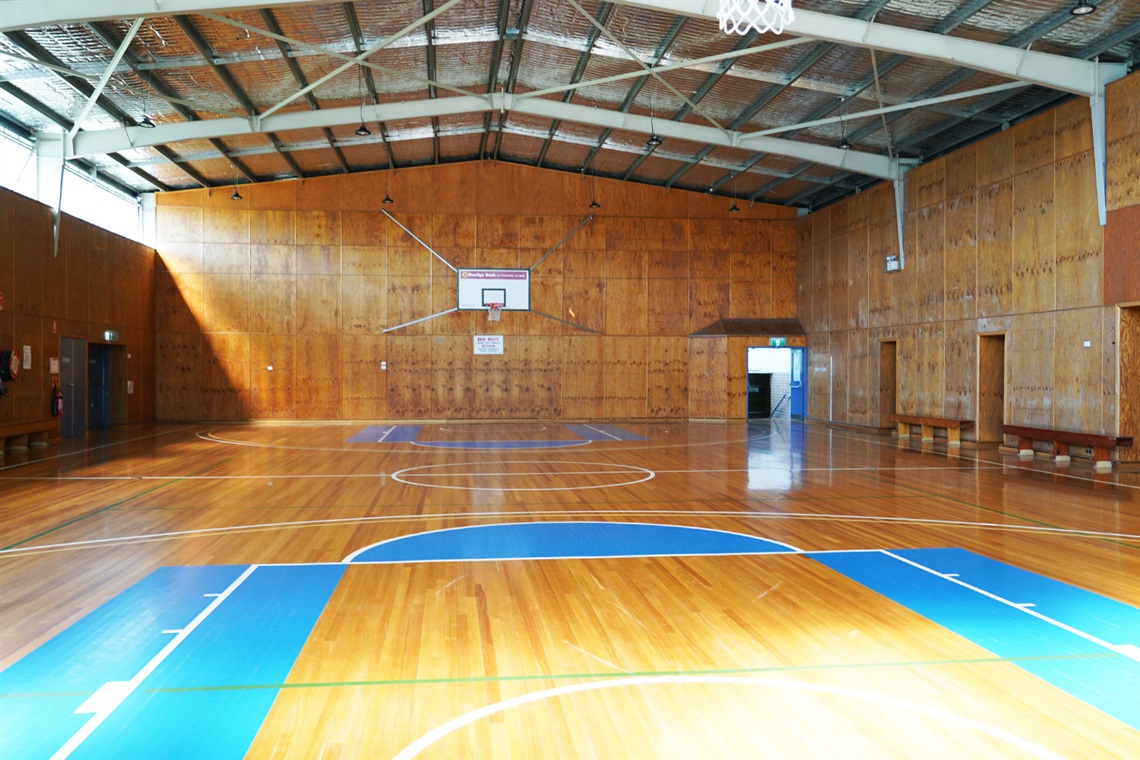A view of the court from underneath one of the hoops. There is a strip of windows near the roof on the left wall letting in natural light.