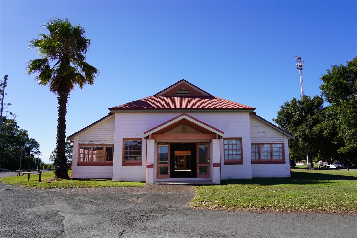 Complete front view of Nowra Showground Committee Room building with lawn and sealed roadway.
