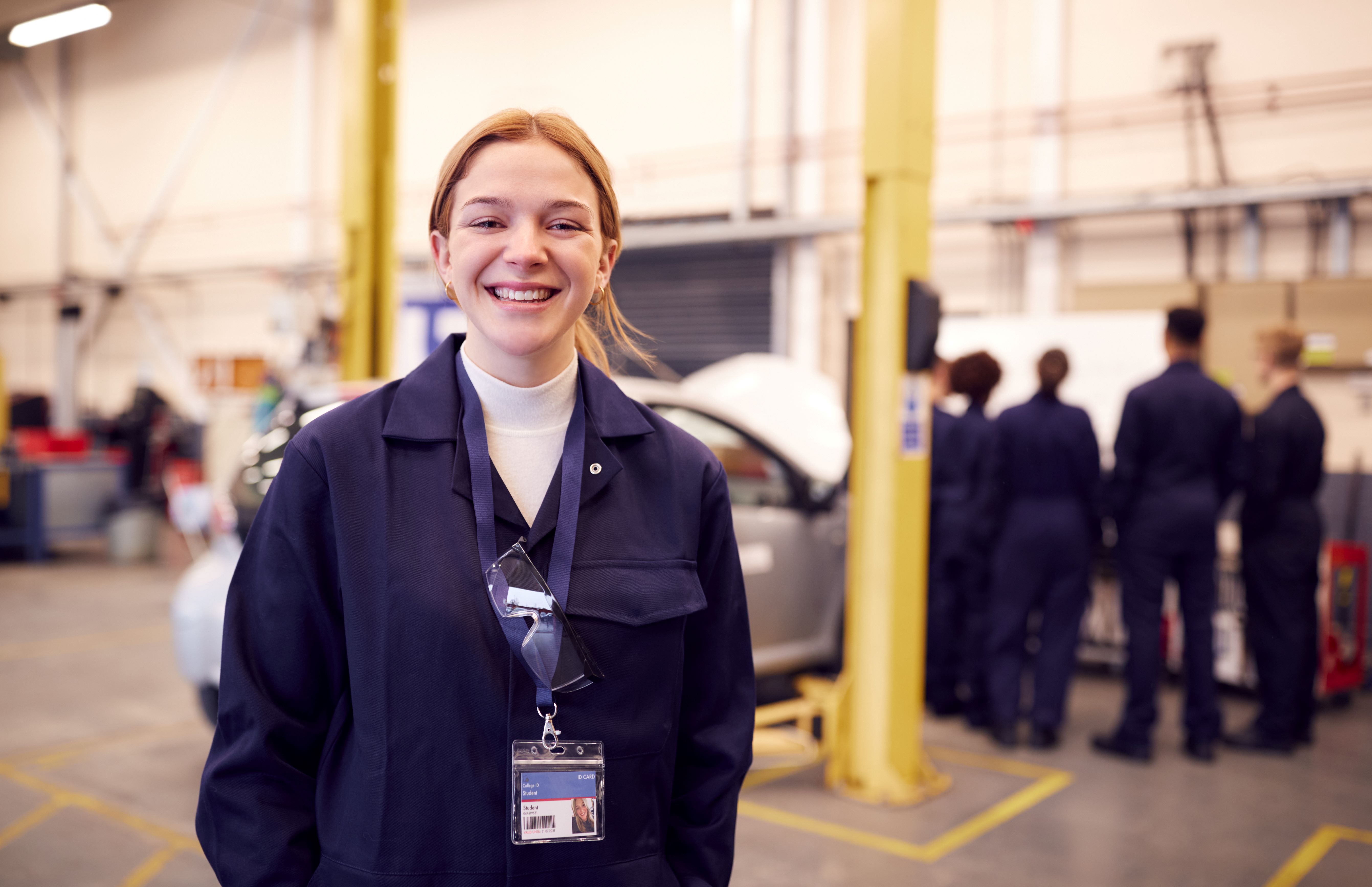 A young person in a mechanic shop smiling at the camera