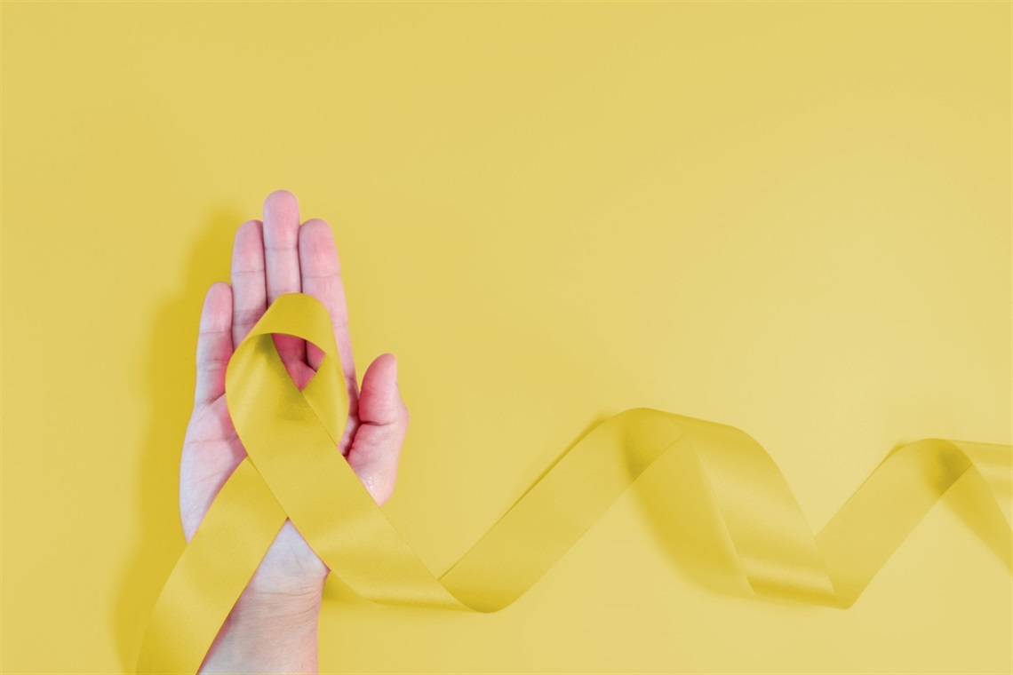 Image of a human hand holding a yellow ribbon