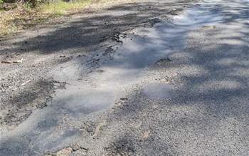 Pavement damage along Gerroa Road that has been patched.