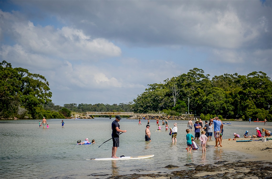 Groups of adults and children wading in the calm waters of a creek