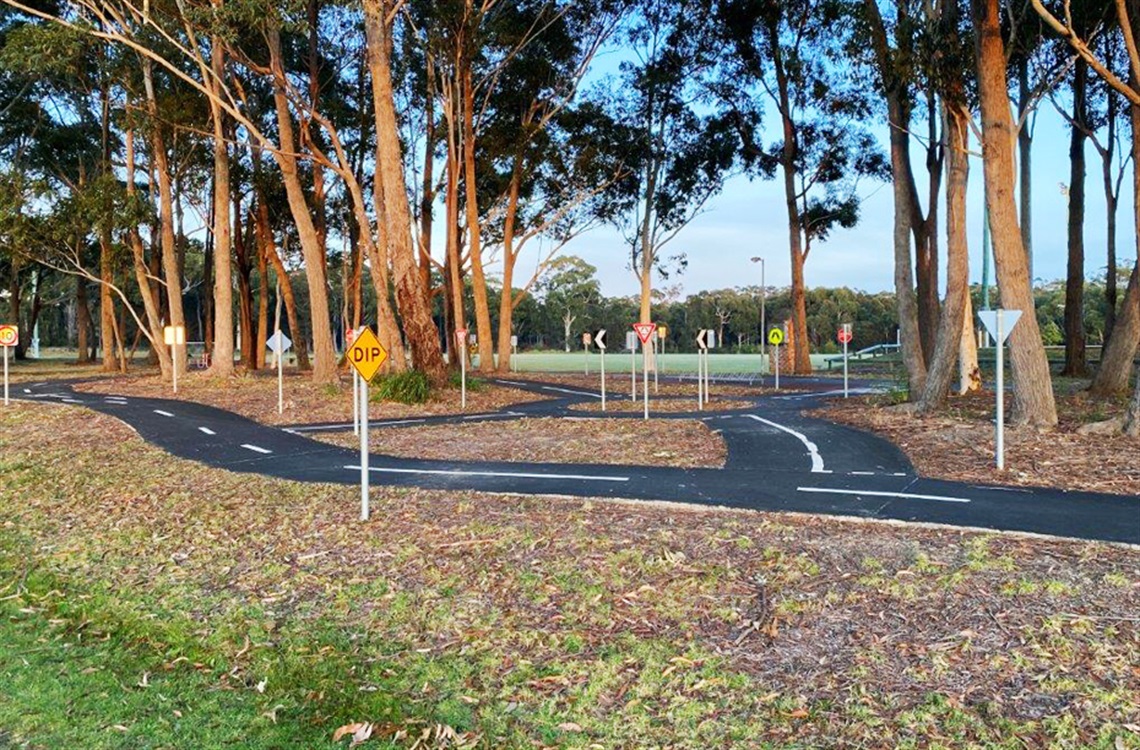 Learn to ride path with various traffic signs in front of tall trees